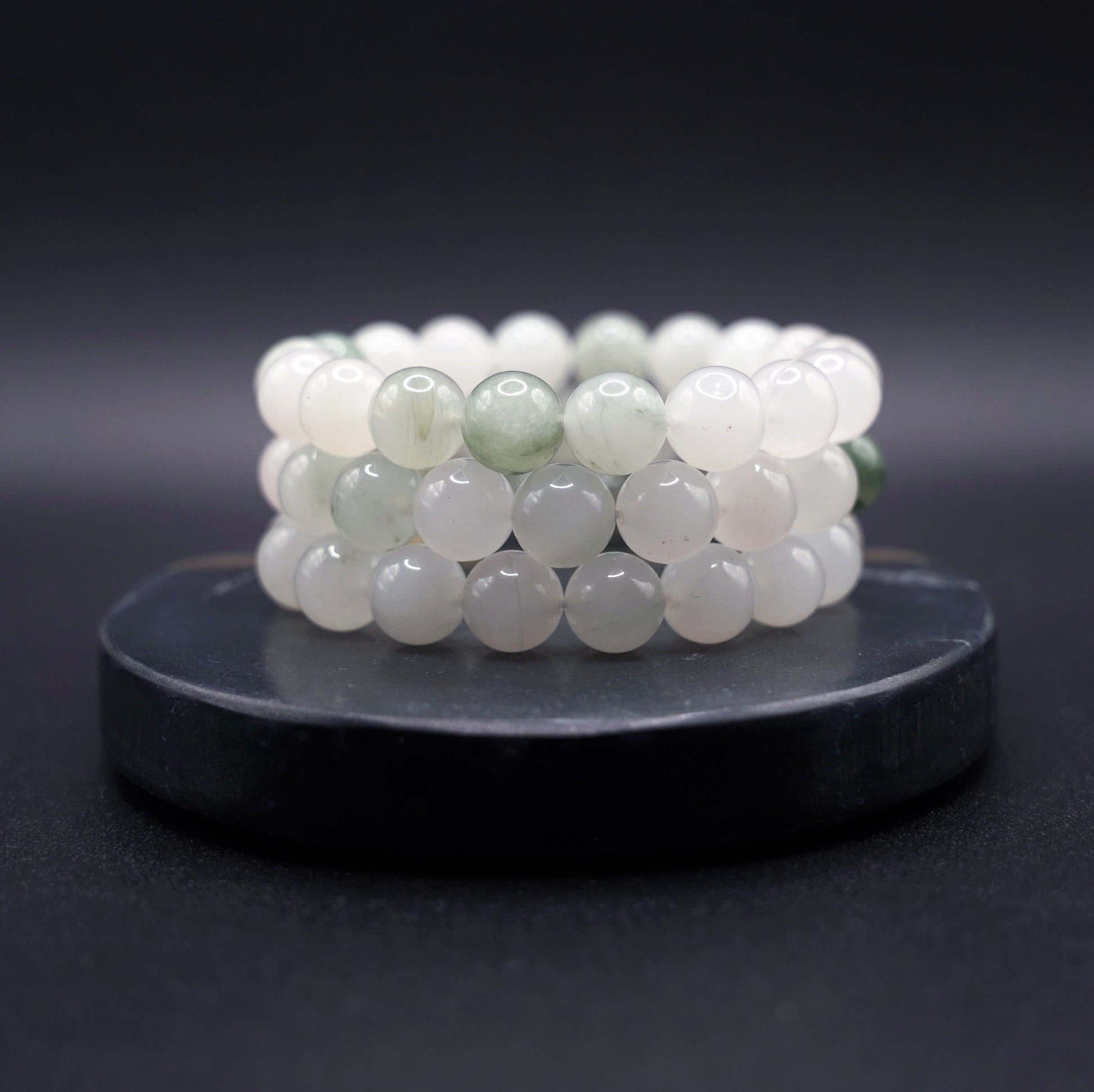 Layered jade bracelets featuring natural jadeite beads in soft green hues, styled for luxury and spiritual elegance