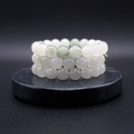 Layered jade bracelets featuring natural jadeite beads in soft green hues, styled for luxury and spiritual elegance
