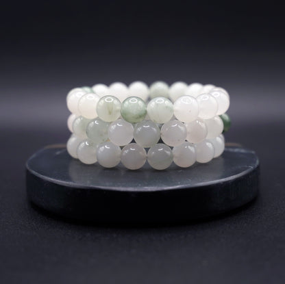 Layered jade bracelets featuring natural jadeite beads in soft green hues, styled for luxury and spiritual elegance